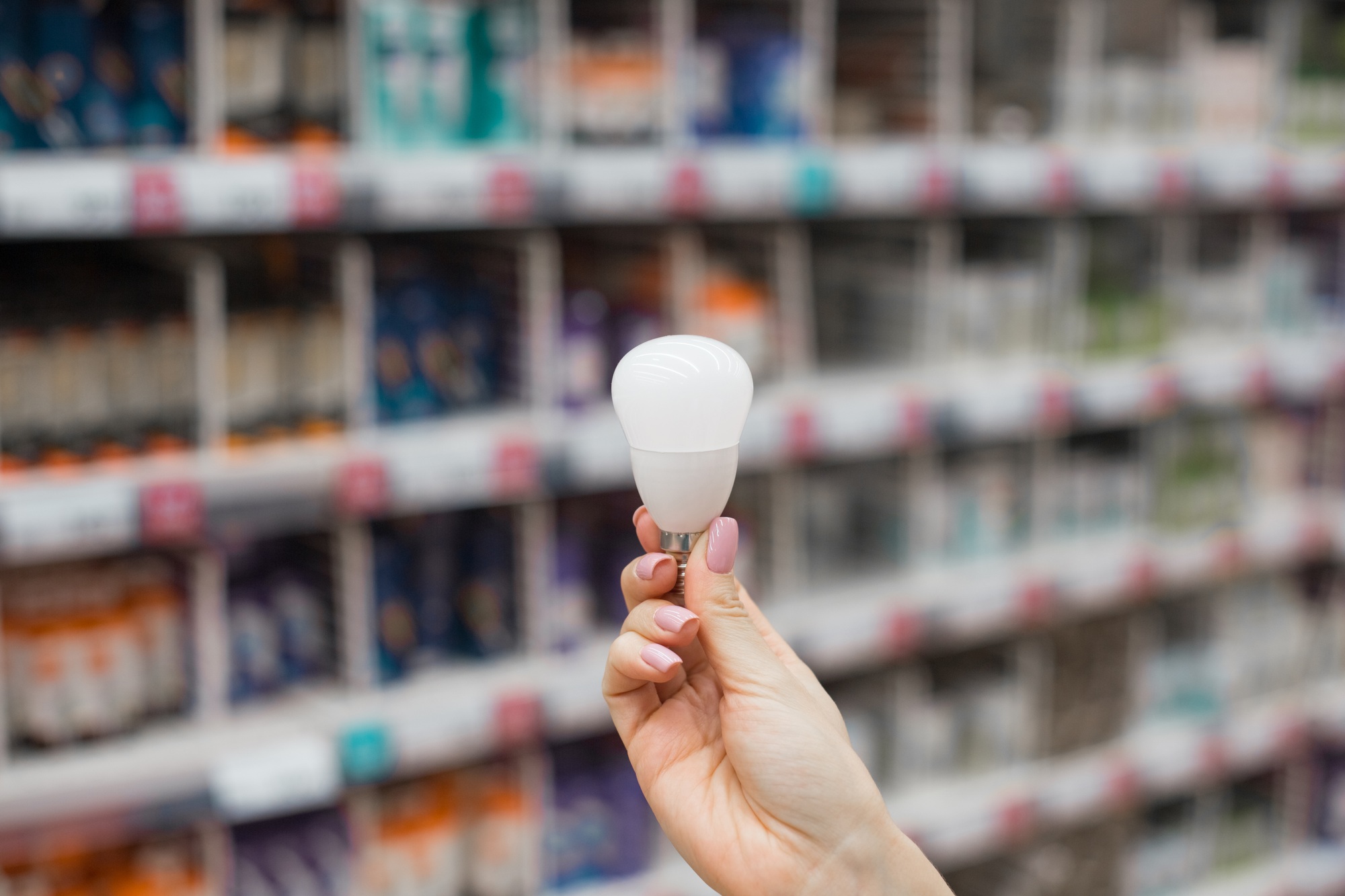 A young woman chooses and buys a light bulb in the store. Home lighting. Close-up