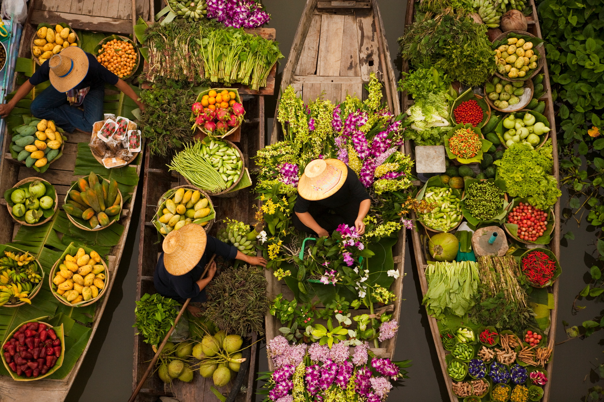 Aerial view of a floating market on a canal in Bangkok, local boats laden with fresh food, moored