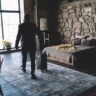 Anonymous man with suitcase in luxurious hotel room