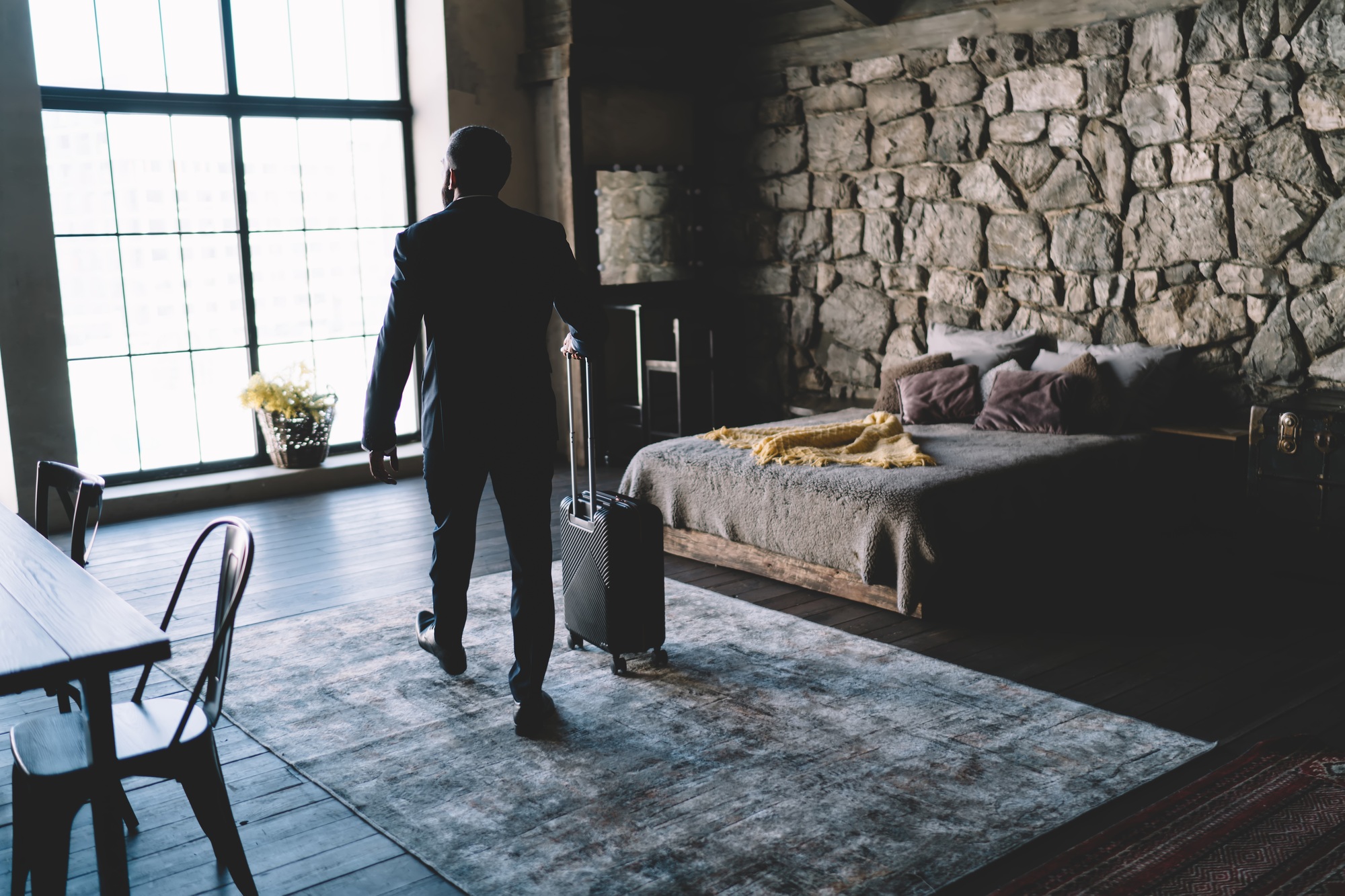 Anonymous man with suitcase in luxurious hotel room