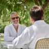 happy mature man in sunglasses and robe chatting with wife in summer garden, wellness retreat