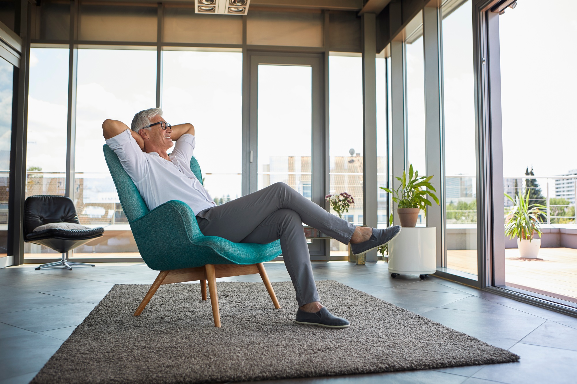 Smiling mature man relaxing in armchair at the window at home